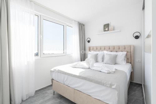 a bedroom with a bed with white sheets and a window at Elegant Seaview 1bd in Dobre Vode in Dobra Voda