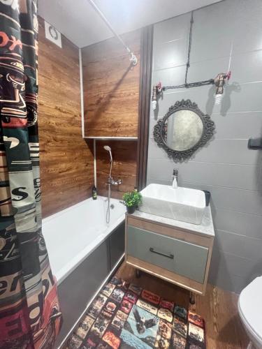 a bathroom with a sink and a tub and a mirror at Лофт в самом сердце Караганды in Karagandy