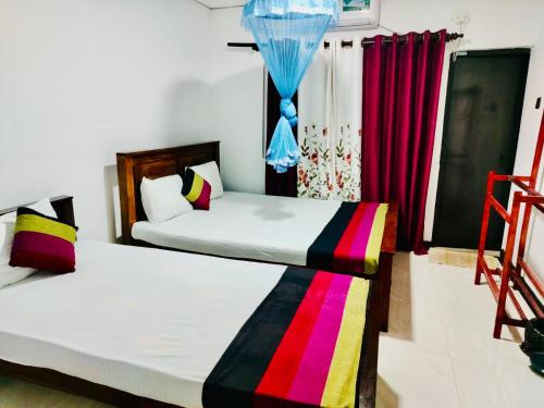 two beds in a room with red curtains at Malwathu oya resort in Anuradhapura