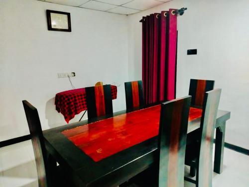a dining room with a red table and chairs at Malwathu oya resort in Anuradhapura