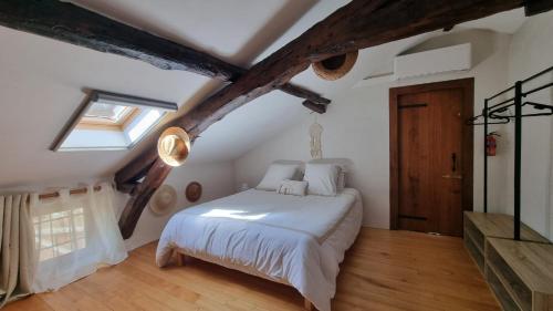 a bedroom with a white bed in a attic at Gîte et chambres d'hôtes Aux Charlots in Lagarde-Hachan