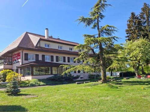 a large house with a tree in front of it at The Originals City, Hôtel Rey du Mont Sion, Saint-Julien-en-Genevois Sud in Saint-Blaise