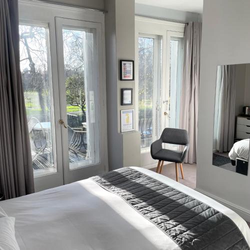 a bedroom with a bed and a chair and windows at Hotel 63 in London