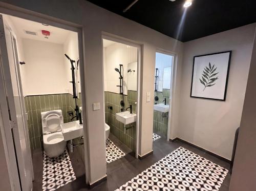 a bathroom with two sinks and a toilet and a mirror at Straits Heritage Hostel in Singapore