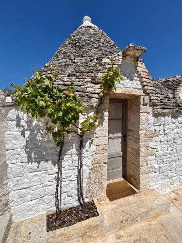 a stone building with a tree in front of it at Trullo Soave Suite - outdoor jacuzzi in Alberobello