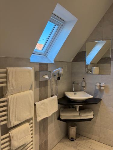 a bathroom with a sink and a skylight at Hôtel de l'Ange in Niedermorschwihr