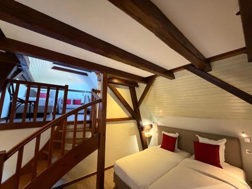 a small room with a bed and a staircase at Hôtel de l'Ange in Niedermorschwihr