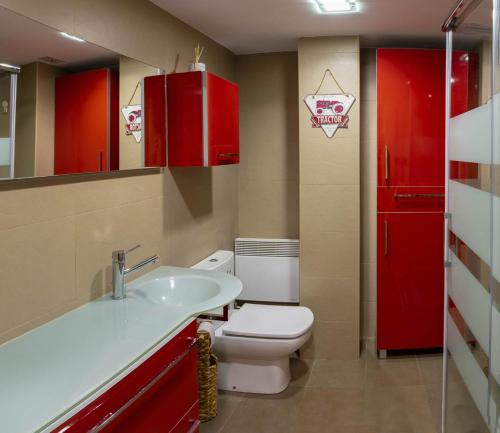 a bathroom with a toilet and a sink and red cabinets at Ibon de Anayet in Formigal