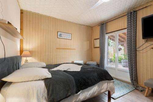a bedroom with a bed and a tv and a window at La Cabane du Bassin in Lanton