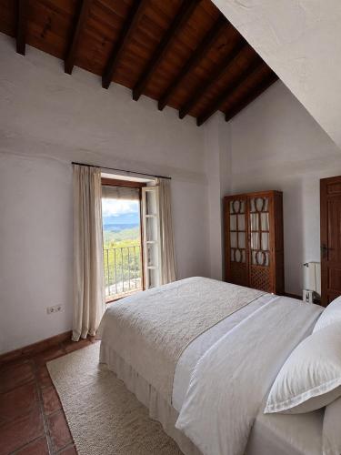 a bedroom with a large bed and a window at Finca Soleá in Zahara de la Sierra