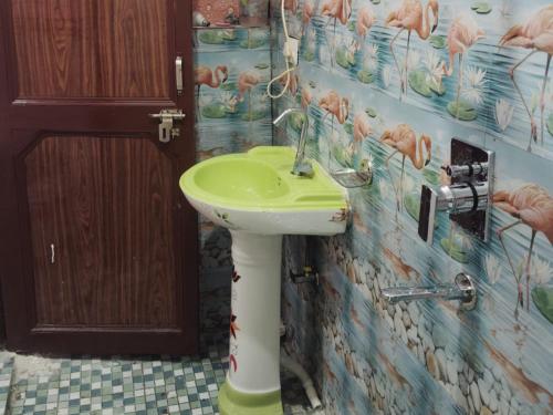 a bathroom with a green and white sink on the wall at Royal Orbit By StayApart in Sonprayag