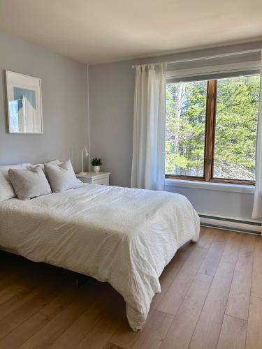 a bedroom with a large bed and a large window at Chalet «L'Autrichien» de Charlevoix in Petite-Rivière-Saint-François
