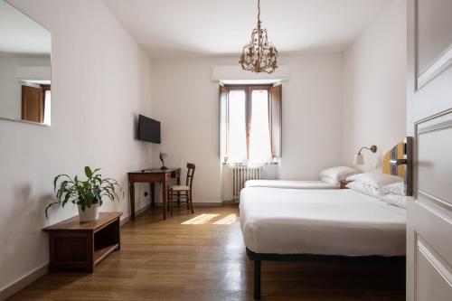a bedroom with two beds and a table and a chandelier at Hotel Verdi Pisa in Pisa