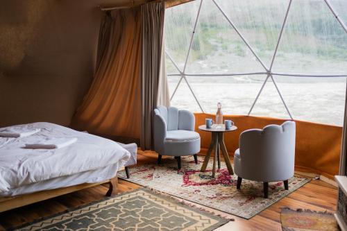 a bedroom with a bed and two chairs and a window at Camp The Sanga Manali in Tāndi
