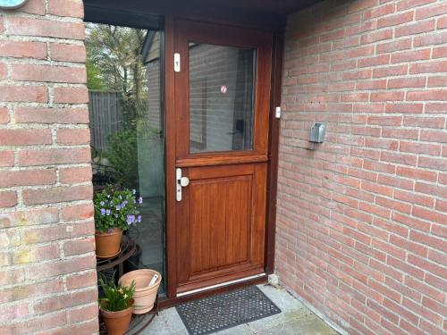 a wooden door on a brick house with potted plants at Seasons in Warmenhuizen