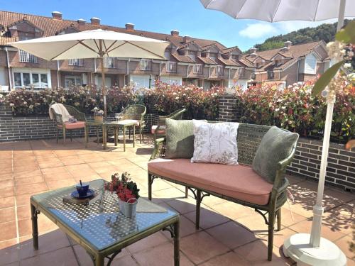 a patio with chairs and tables and an umbrella at Casa El Robledal 5925 in Arnuero