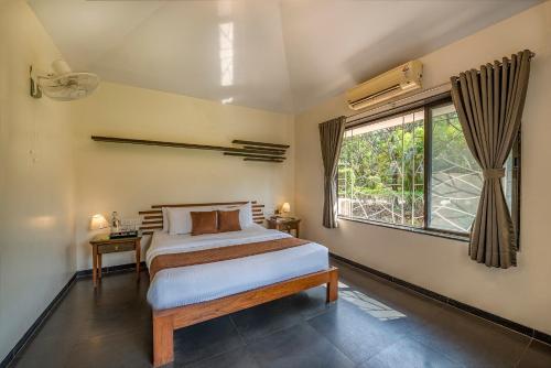 a bedroom with a bed and a large window at Palmwoods Retreat in Pune