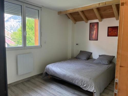 a bedroom with a bed and two windows at Chalet de montagne, très confortable, neuf in LʼArgentière-la-Bessée