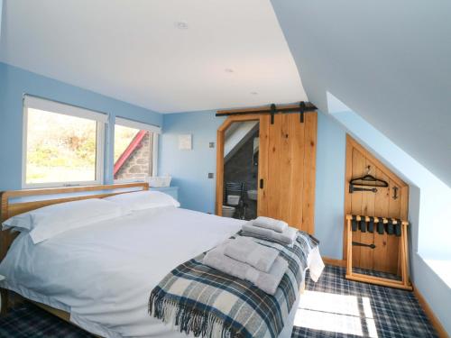 a bedroom with a white bed and a window at Post Cottage in Arisaig