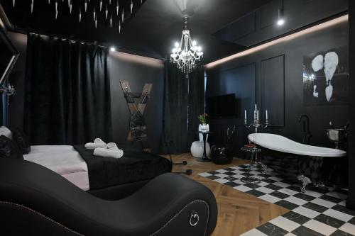 a black room with a bed and a bath tub at Love Krak-Off - BDSM Old Town in Krakow