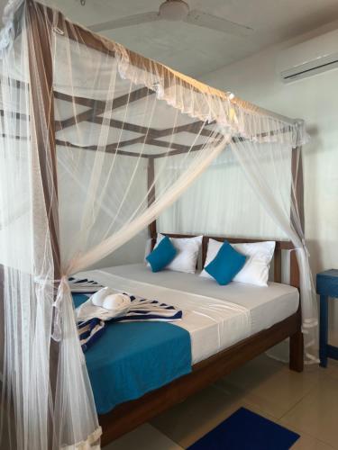 a bedroom with a canopy bed with blue and white pillows at Check Point in Unawatuna