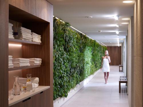 a woman walking down a hallway with a green wall at Giardino Marling in Merano
