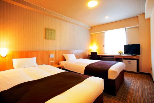 a hotel room with two beds and a television at Nest Hotel Sapporo Ekimae in Sapporo