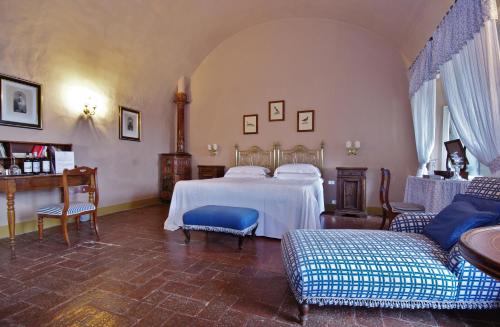 a bedroom with a bed and a couch and chairs at Badia a Coltibuono Wine Resort in Gaiole in Chianti