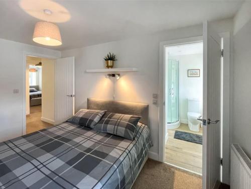 a bedroom with a checkered bed and a bathroom at Borders Cottage in Coldstream