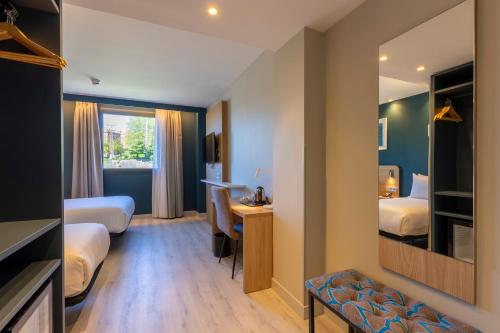 a hotel room with two beds and a desk at Travelodge Bilbao Sestao in Sestao