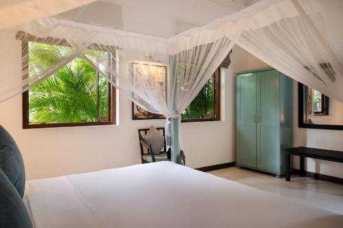 a bedroom with a bed with white curtains and a window at Ranna Beach House in Ranna