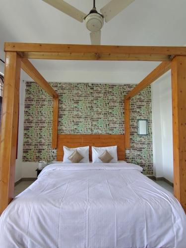a large bed in a bedroom with a brick wall at Pinewood Sunrise Homestay Kasauli by Splendid Retreat Hotels in Kasauli