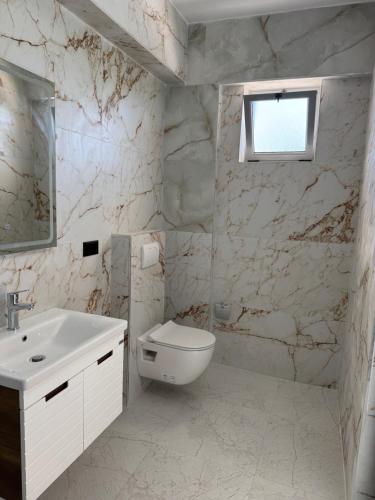 a white bathroom with a sink and a toilet at Hotel Irini in Sarandë