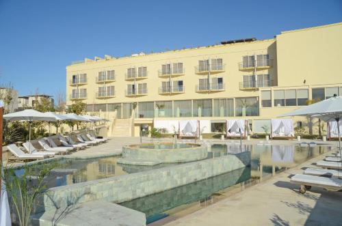 un hotel con piscina y sillas y un edificio en E-Hotel Larnaca Resort & Spa en Lárnaca