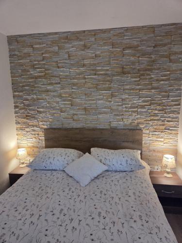 a bed with two pillows and a brick wall at Apartment Maro in Šibenik