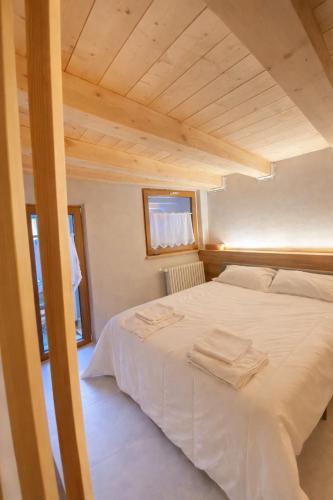 ein weißes Bett in einem Zimmer mit Holzdecke in der Unterkunft Boutique Alpine Studio by SupaStays in Courmayeur