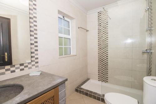 a bathroom with a sink and a toilet and a shower at Villa Florencio by Algarve Holidays in Estói