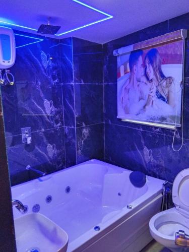 a bathroom with a tub and a poster of a couple at Hotel Bellemount in Ahmedabad