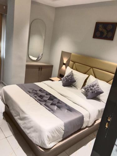 a bedroom with a large bed with white sheets and blue pillows at Hotel Bellemount in Ahmedabad