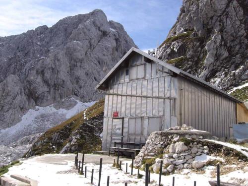 a building on a snowy mountain with a mountain at Zavetišče pod Špičko in Soča