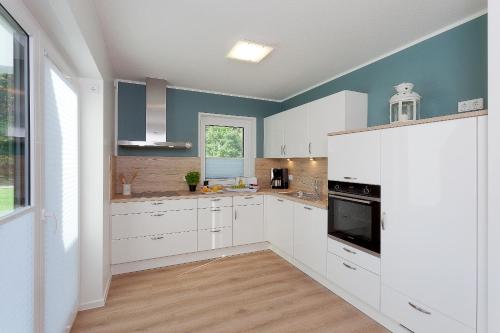 a kitchen with white cabinets and blue walls at Ferienwohnung Justus in Karlshagen