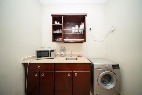 a kitchen with a sink and a microwave and a washer at The Home Dreamland in 6th Of October