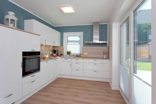a kitchen with white cabinets and a large window at Ferienwohnung Justus in Karlshagen