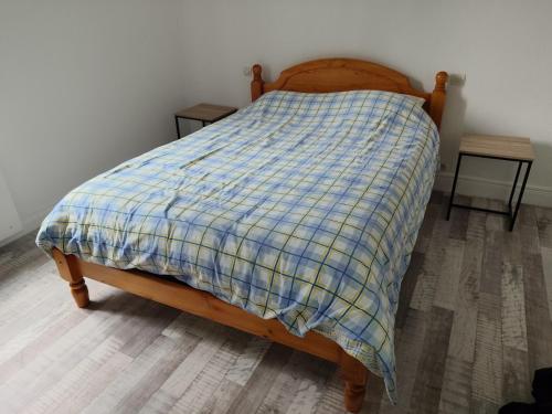 a bed with a blue and yellow plaid blanket on it at Location maison in Neussargues-Moissac