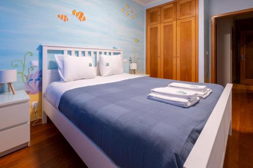 a bedroom with a bed with towels on it at FamilyHub - EcoHost - Spacious 3-bedroom apartment for 8 people with AC and parking near Porto and the beaches in Senhora da Hora
