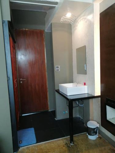 a bathroom with a sink and a wooden door at 75 StangStay & Cafe de Art in Ka Rorn