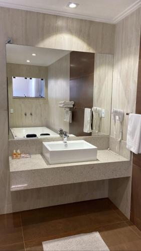 a bathroom with a sink and a large mirror at POUSADA ESTÂNCIA in Penedo