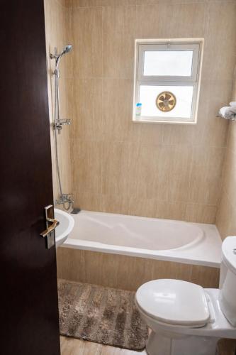 a bathroom with a tub and a toilet and a window at Spacious Apartment in Amman
