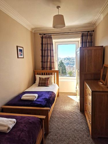 a small bedroom with a bed and a window at McCaig's Tower Apartment in Oban