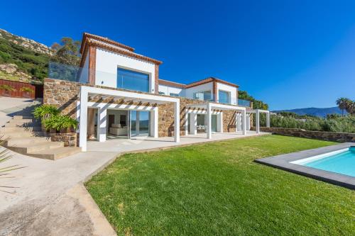 a villa with a swimming pool and a yard at Villa Las Palmeras Valdevaqueros Suites, Pool & Sea Views in Tarifa